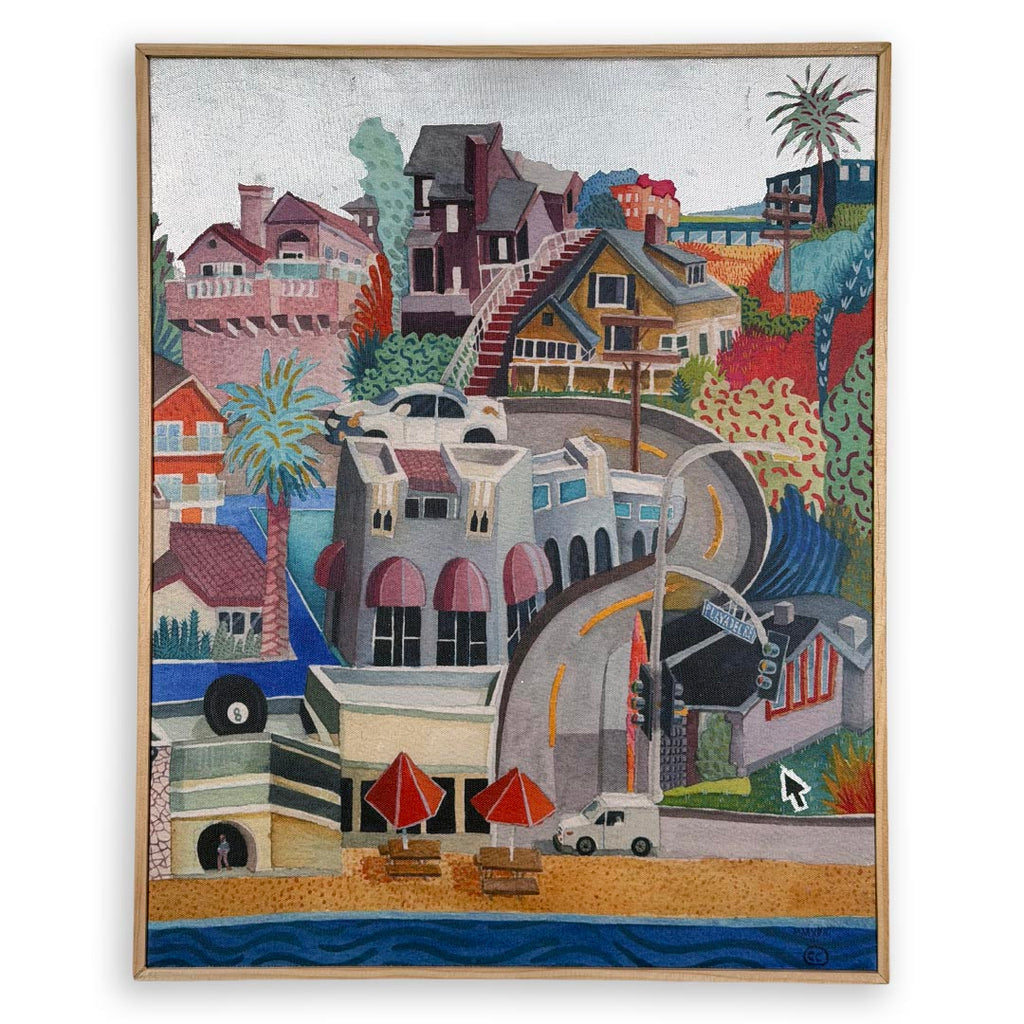 A framed colorful painting depicting a coastal hillside town with houses, palm trees, a curved road, beach umbrellas, and blue ocean water at the bottom. White background, silver foil sky.