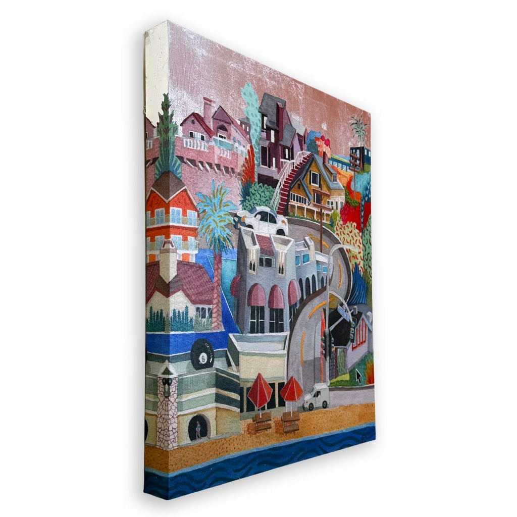 A stylized multicolor canvas wall art print depicting a coastal town with houses, palm trees, a beach, and blue water, shown at an angle against a white background. Silver foil sky.