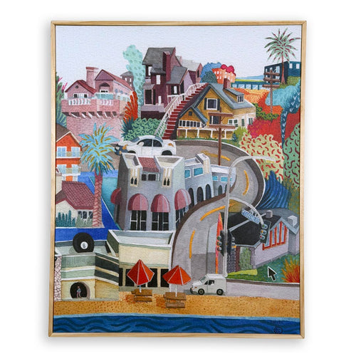 A framed colorful painting depicting a hillside coastal town scene with houses, palm trees, a winding road, beach umbrellas, and ocean water, shown against a plain white background.